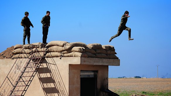 Three young YPG fighters prepare to leap from their lookout near the village of Tel Marouf, freed from the Islamic State two days before. 