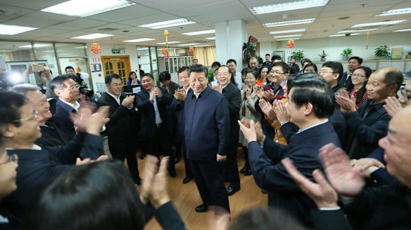 Workers applaud as Chinese President Xi Jinping talks with staff at the People's Daily in February.