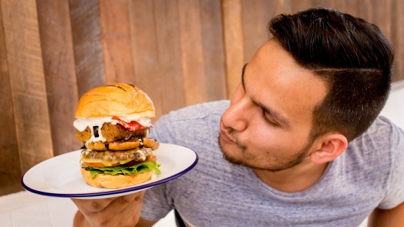 Owner Amit Tewari with one of his ingredient-stacked burgers.
