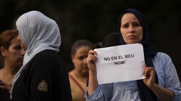 A woman in Ripoll holds a placard stating in Catalan "not in my name".
