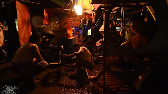 Two men repair a tyre in one of the alleys of Tondo district in Manila.