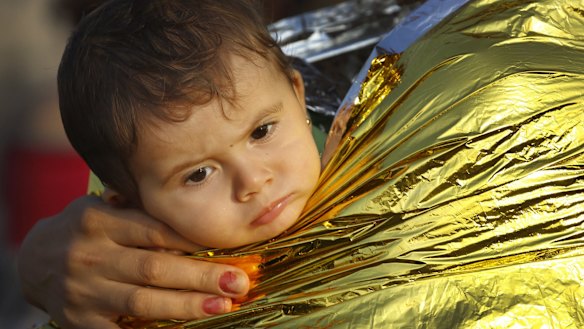 A Syrian refugee child is covered by thermal blanket in Kos following a rescue mission on Monday.