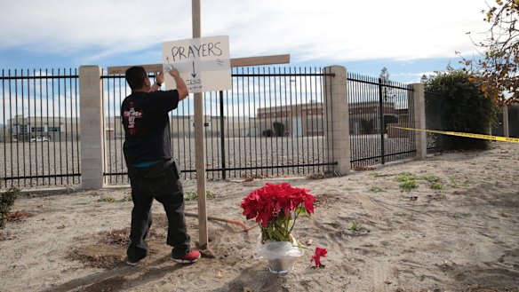 A cross and a sign outside the police perimeter around the Inland Regional Centre, the site of a mass shooting that left 14 dead and 21 wounded, in San Bernardino, California.