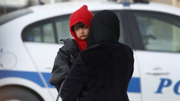 A Syrian woman holds a child and waits for information regarding the possible opening at the closed Turkish border crossing with Syria in the outskirts of the town of Kilis, in south-eastern Turkey on Wednesday. 