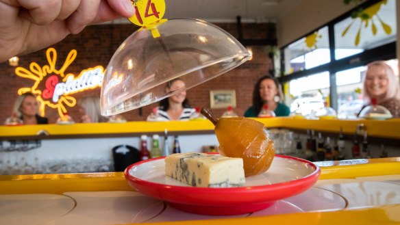 Cheeses trundle by on colour- and price-coded plates.