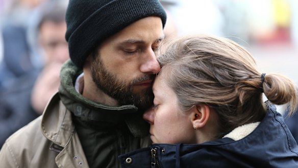 A couple embrace after laying flowers at the La Belle Equipe cafe