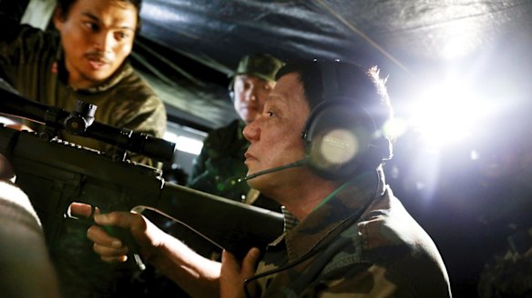 President Rodrigo Duterte holds an assault rifle during a visit to Marawi in southern Philippines.