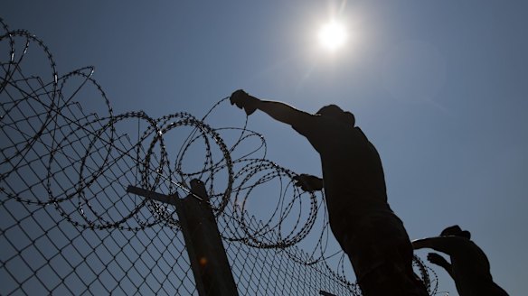 Hungarian soldiers put up razor wire on top of a fence on the border with Serbia, in Asotthalom, Hungary.