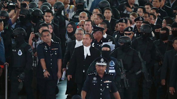 High court judge Azmi Ariffin, wearing glasses at centre, arrives with lawyers at the check-in kiosk during the re-enactment with suspects in the murder of Kim Jong-nam.