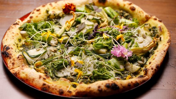 Supergreen pizza topped with pesto, zucchini, broccolini and pepitas.