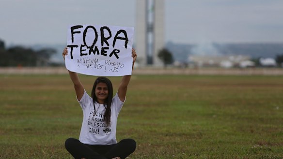 A woman holds up a poster with a message that reads in Portuguese; "Get out Temer, do not take any more of our rights" during an isolated protest in the center of Brasilia on Friday.