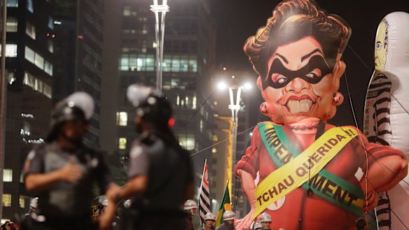 Police officers stand next to a large inflatable doll in the likeness of Brazil's President Dilma Rousseff wearing a presidential sash with the words in Portuguese "Goodbye dear" during a rally to celebrate her impeachment in Sao Paulo.