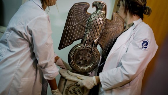 Members of Argentinian federal police carry a Nazi statue found hidden in a house in Buenos Aires.