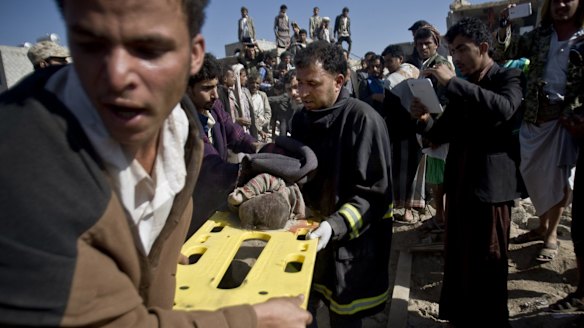 Yemenis carry the body of a child from houses hit by Saudi air strikes near Sanaa Airport on March 26.