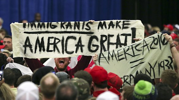 A protester holds up a sign as he disrupts a rally for Republican presidential candidate Donald Trump.
