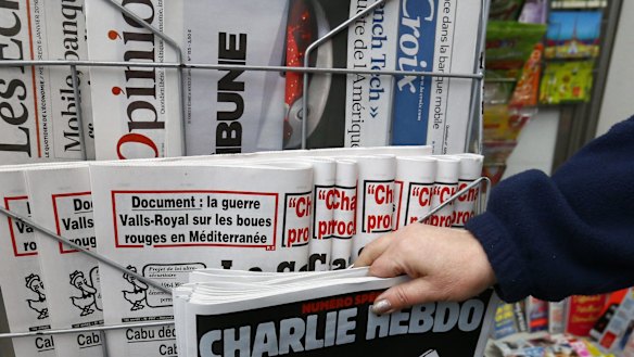 A woman picks up the issue of Charlie Hebdo that marks one year after the attacks on the French satirical newspaper.