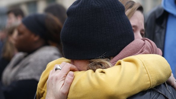 People hug in the street in front  of the Carillon cafe and the Petit Cambodge restaurant in Paris on Saturday.