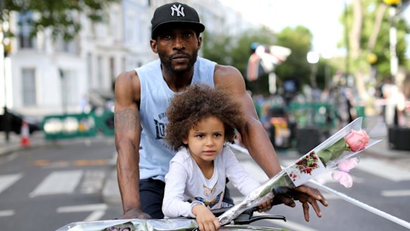 A young girl carries a flower as she rides with an adult near Grenfell Tower on Thursday.