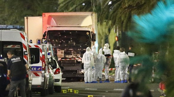 French police forces and forensic officers stand next to a truck that ran into a crowd in Nice.