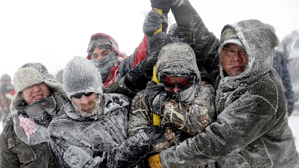 Veterans huddle together to hold a US flag against strong winds during a march to protest the Dakota Access pipeline in Cannon Ball, North Dakota, in December.