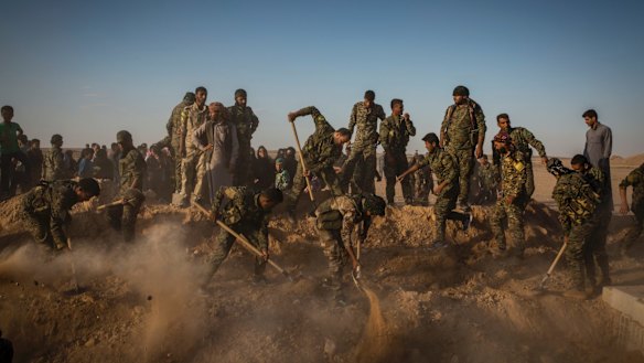 Syrian Democratic Forces militiamen bury their comrade Omar al-Abed, who they say  died after grabbing an Islamic State suicide bomber to shield his comrades.