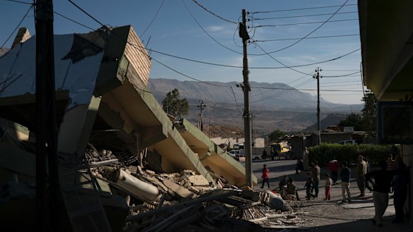 People walk next to a destroyed house after an earthquake in the city of Darbandikhan, northern Iraq, on Monday.