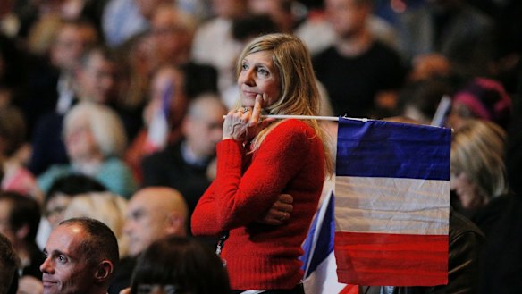 A woman holds a French national flag during a presidential campaign rally in Paris on Monday.