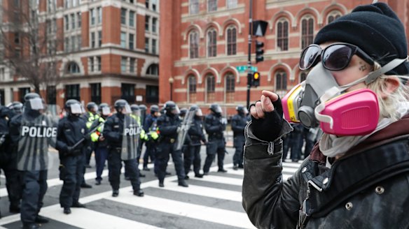 A protester faces off with a line of riot police after the inauguration.