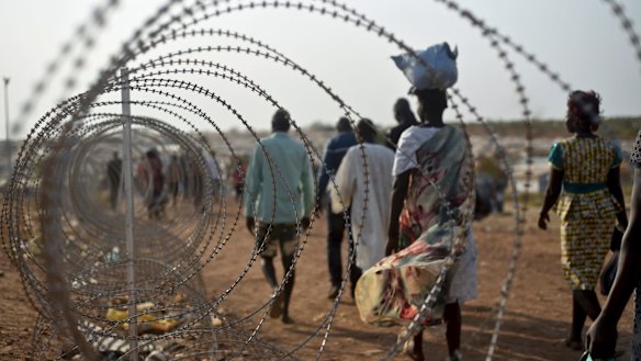 Displaced people walk next to a razor wire fence at the United Nations base in the South Sudanese capital Juba last year.  The country's brutal civil conflict has prompted an epidemic of sexual violence.