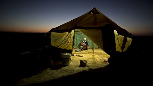 A Syrian refugee woman tends to her daughter while cooking inside her tent at an informal settlement near the Syrian border on the outskirts of Mafraq, Jordan, in August.