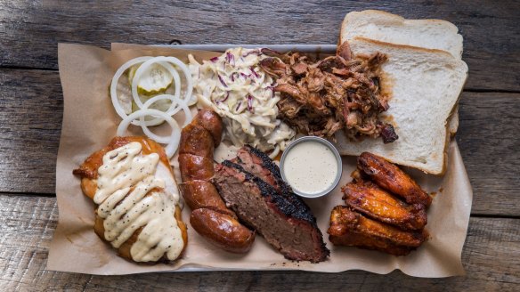 "Pitmaster selection" platter (clockwise from top right) pulled pork, buffalo hot chicken wings, brisket, house-made sausage, smoked chicken breast with Alabama-style white sauce, pickles and coleslaw.