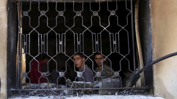 Palestinians look out of the burned home of the Dawabshe family in the village of Duma.
