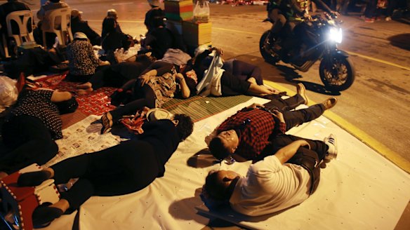 Thai police ride past supporters of former Prime Minister Yingluck Shinawatra sleeping outside the Supreme Court ahead of Friday's scheduled verdict.
