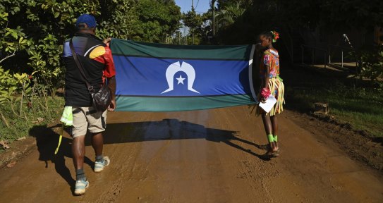 The Torres Strait flag is carried during the Mabo Day parade on Boigu Island, commemorating the first successful native claim in Australia on the 3rd of June, 1992. Thursday Island, Torres Strait. 3rd June, 2021. Photo: Kate Geraghty 

