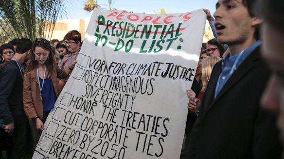 Environmental activists at the Climate Conference in Marrakech, Morocco, hold a banner urging then president-elect Donald Trump to act on climate change.