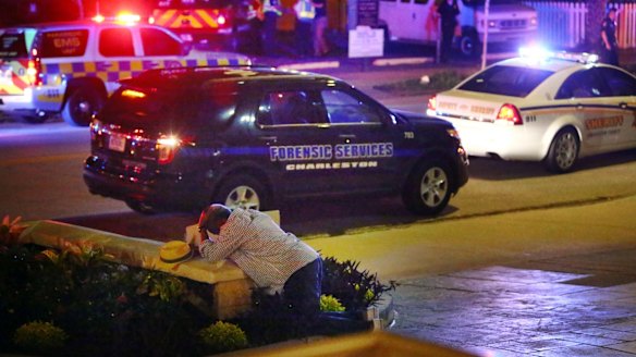 A man kneels across the street from where police gather outside the Emanuel AME Church following a shooting Wednesday.