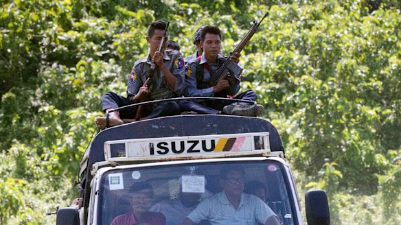 Myanmar police travel on the roof of a truck carrying local UN staff as they flee the violence on August 28.