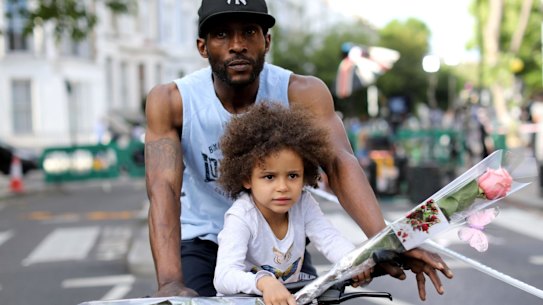 A young girl carries a flower as she rides with an adult near Grenfell Tower on Thursday.