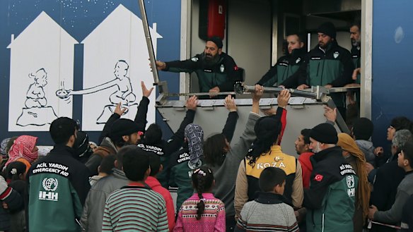 Syrians gather to collect food at a temporary refugee camp in northern Syria, near the Bab al-Salameh border crossing with Turkey.