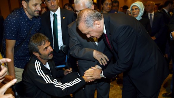 Mr Erdogan, right, shakes hands with a wounded civilian during an event to honour those killed and wounded during the failed coup.