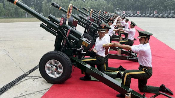 Paramilitary policemen and members of a gun salute team load cannons during a training session in Beijing.