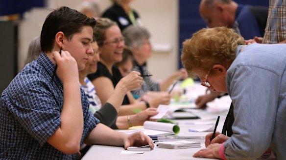 A student election official helps woman sign in for voting, in St Louis, Missouri.