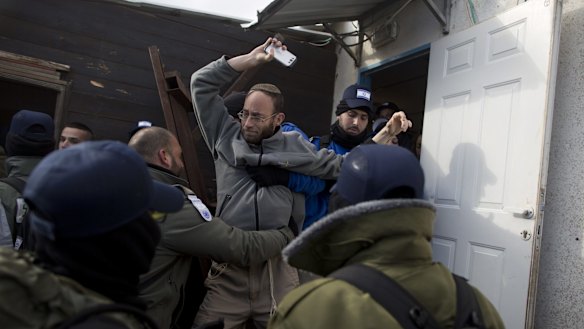 A settler holding a mobile phone is arrested during the evacuation.