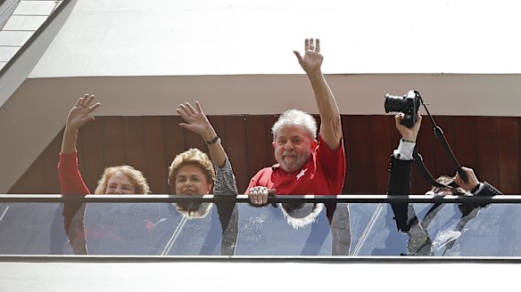 Brazil's former president Luiz Inacio Lula da Silva, right, with President Dilma Rousseff, centre, and Lula's wife, Marisa Leticia, left, wave to supporters from the balcony of his home on Saturday.
