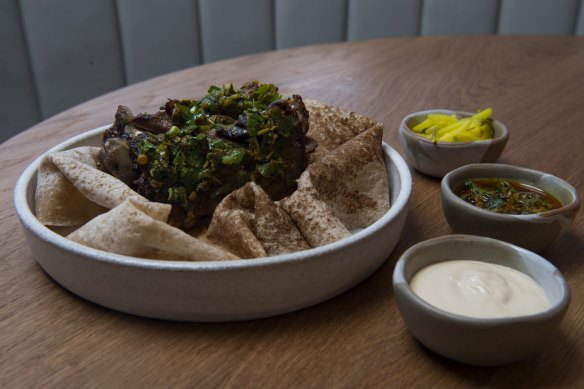 Lamb neck shawarma with tarator, pickles, chermoula and flatbread.