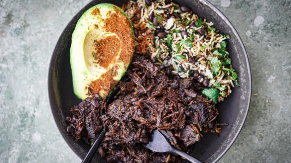 Mexican beef cheek stew with beans, rice and avocado sprinkled with some spice.