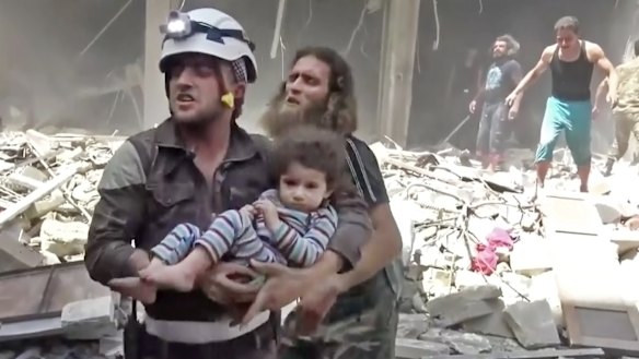 A Civil Defence worker carries a child after air strikes hit Aleppo.