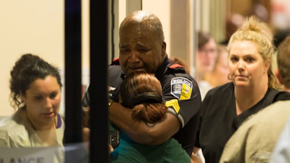 A Dallas Area Rapid Transit police officer receives comfort at the Baylor University Hospital emergency room entrance.