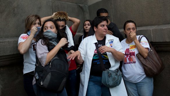 People protect themselves from tear gas in Rio de Janeiro, on Friday.