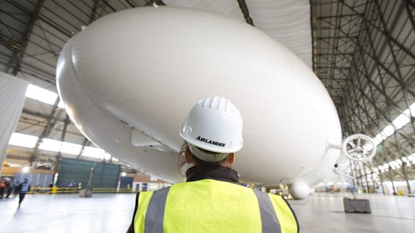 A worker stands in front of the Airlander 10 hybrid airship.